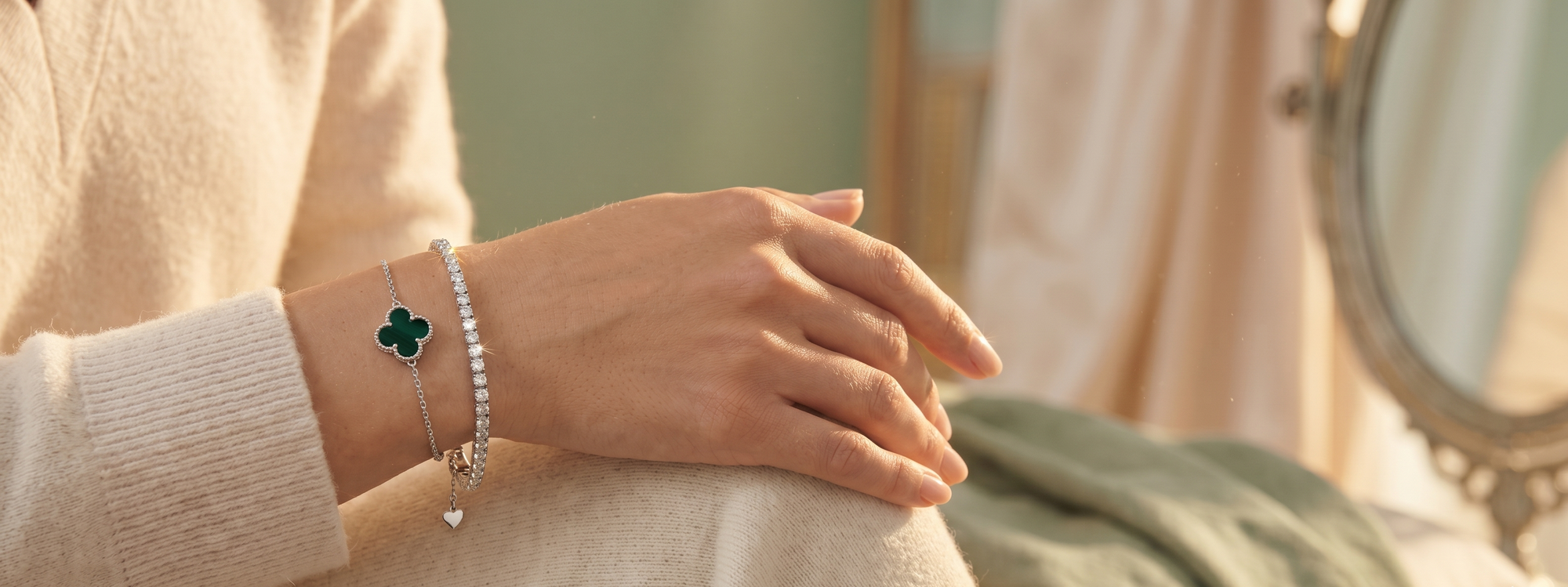 Hand wearing a bracelet with a clover charm on a blurred background