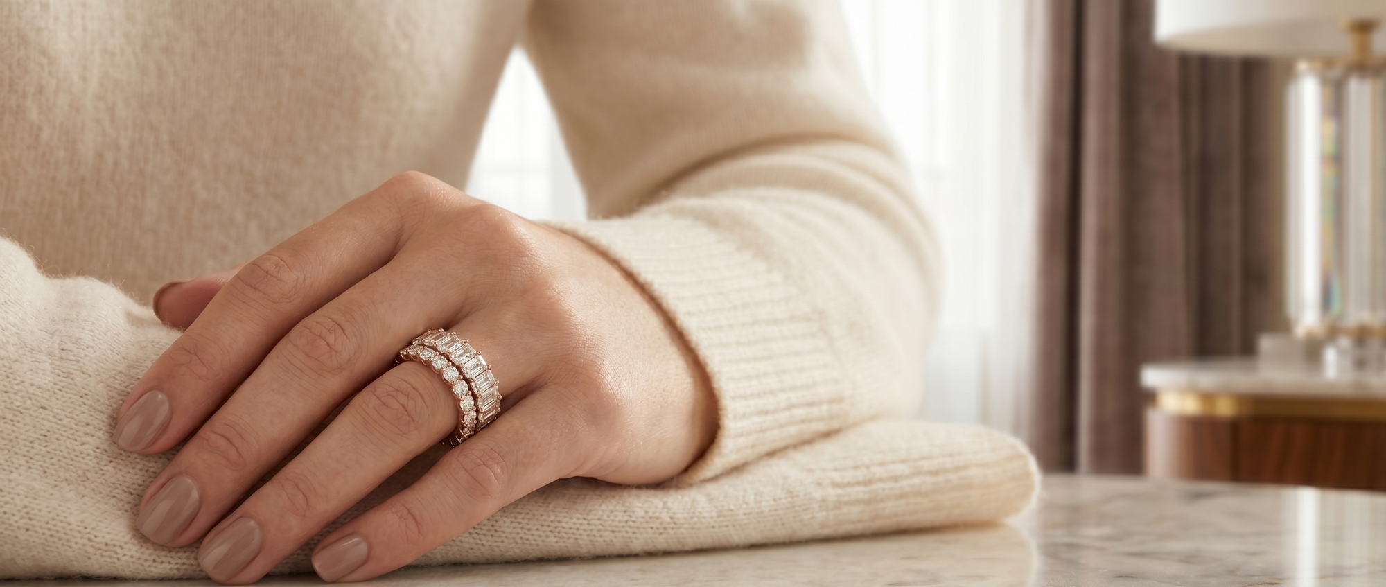 Hand wearing a diamond ring on a neutral background